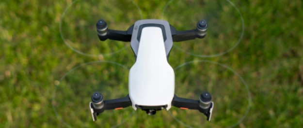 A white drone flying over grass